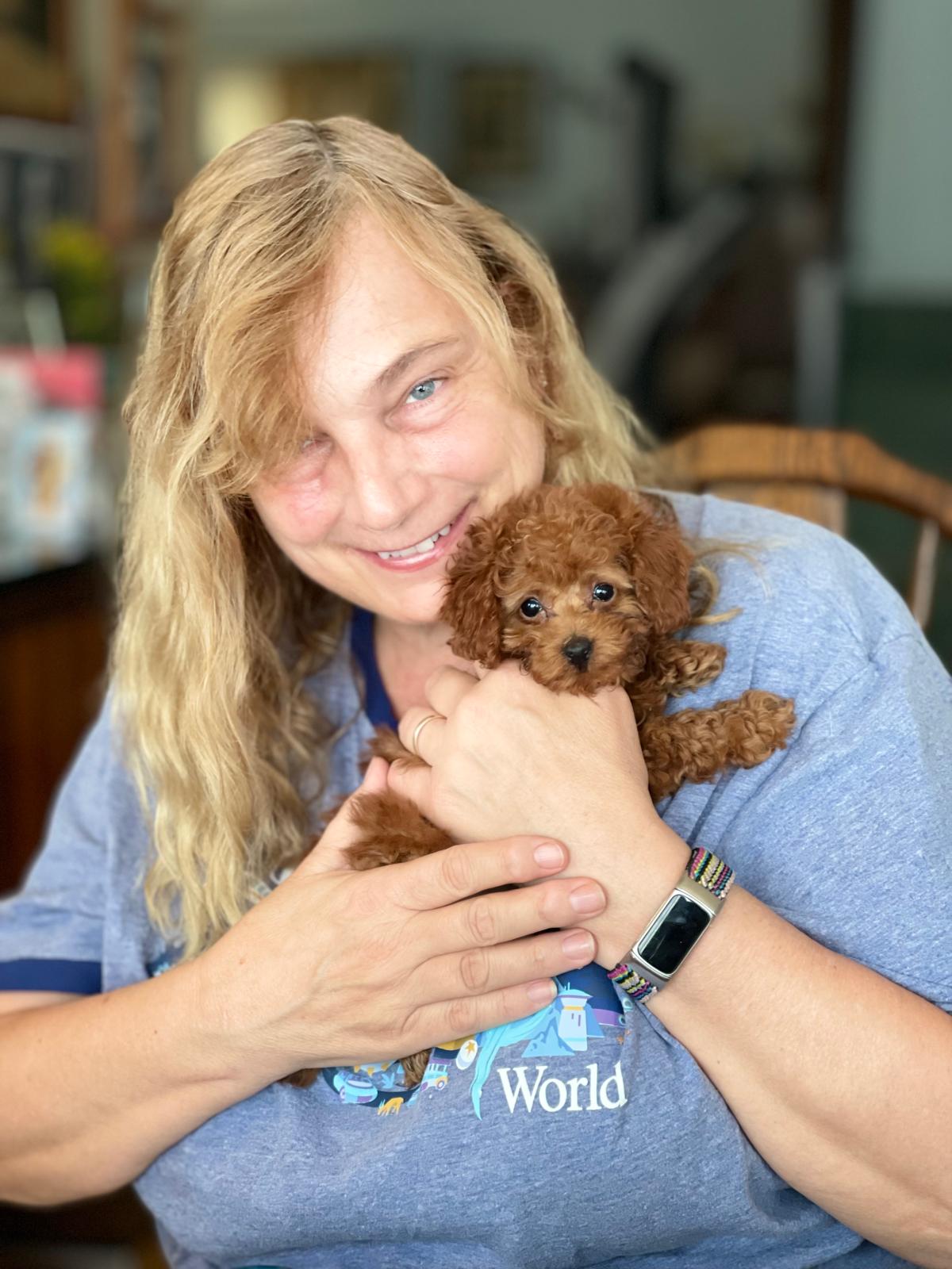 Woman holding a tiny red Toy Poodle puppy